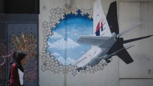 a-woman-walks-past-graffiti-of-the-missing-malaysia-airlines-BKSZJU4BBRDRFEZZHW33OXD3HU