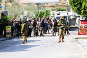 Israeli soldiers stand alert while guarding Jewish settlers